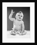 1950s portrait of baby sitting one arm raised waving by Anonymous