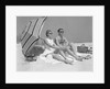 1960s couple in sunglasses sitting on beach blanket with legs extended with umbrella by Anonymous