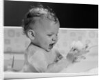 1960s baby in bathtub playing with suds indoor by Anonymous