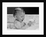 1960s baby in bathtub playing with suds indoor by Anonymous