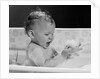 1960s baby in bathtub playing with suds indoor by Anonymous