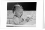 1960s baby in bathtub playing with suds indoor by Anonymous