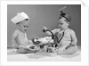 1960s two babies playing doctor and nurse with doll studio by Anonymous