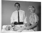 1960s smiling mother and father with twin babies on diaper changing table looking at camera by Anonymous