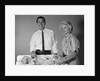 1960s smiling mother and father with twin babies on diaper changing table looking at camera by Anonymous