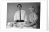 1960s smiling mother and father with twin babies on diaper changing table looking at camera by Anonymous