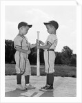 1960s two boys in baseball uniforms choosing sides by getting the upper hand on a bat by Anonymous