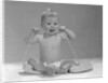 1960s blond baby sitting up looking at camera chewing on telephone cord by Anonymous