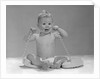1960s blond baby sitting up looking at camera chewing on telephone cord by Anonymous