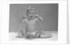 1960s blond baby sitting up looking at camera chewing on telephone cord by Anonymous