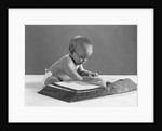 1960s baby wearing glasses looking for a word in big dictionary by Anonymous