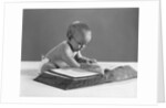 1960s baby wearing glasses looking for a word in big dictionary by Anonymous