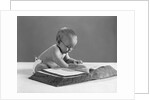 1960s baby wearing glasses looking for a word in big dictionary by Anonymous