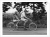 1970s teenage girl and boy riding bicycle built for two by Anonymous