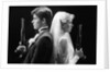1980s bride and groom standing back to back holding dueling pistols by Anonymous
