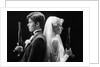 1980s bride and groom standing back to back holding dueling pistols by Anonymous