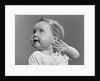 1940s 1950s close-up portrait of baby girl with curl on top of head looking to side with hand held up beside ear by Anonymous