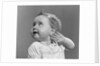 1940s 1950s close-up portrait of baby girl with curl on top of head looking to side with hand held up beside ear by Anonymous