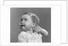 1940s 1950s close-up portrait of baby girl with curl on top of head looking to side with hand held up beside ear by Anonymous