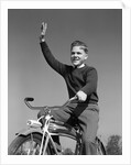 1940s 1950s smiling boy riding bike waving arm in air by Anonymous