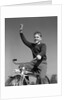 1940s 1950s smiling boy riding bike waving arm in air by Anonymous