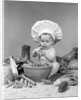 1950s 1960s baby wearing chef hat toque bowl and raw vegetables making a salad by Anonymous