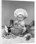 1950s 1960s baby wearing chef hat toque bowl and raw vegetables making a salad by Anonymous