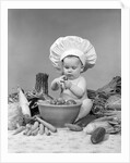 1950s 1960s baby wearing chef hat toque bowl and raw vegetables making a salad by Anonymous