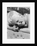 Boy crouching shooting marbles concentration by Anonymous