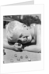 Boy crouching shooting marbles concentration by Anonymous