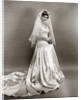 1950s full length portrait bride standing wearing satin and lace wedding gown veil and tiara looking at camera by Anonymous