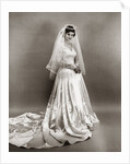 1950s full length portrait bride standing wearing satin and lace wedding gown veil and tiara looking at camera by Anonymous