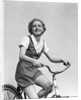 1930s smiling blonde woman riding bicycle looking at camera by Anonymous