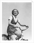 1930s smiling blonde woman riding bicycle looking at camera by Anonymous