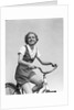 1930s smiling blonde woman riding bicycle looking at camera by Anonymous