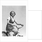 1930s smiling blonde woman riding bicycle looking at camera by Anonymous