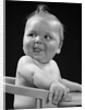 1950s 1940s baby in high chair head turned to one side with tongue sticking out funny facial expression by Anonymous