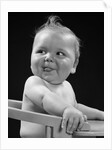 1950s 1940s baby in high chair head turned to one side with tongue sticking out funny facial expression by Anonymous