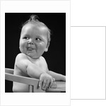 1950s 1940s baby in high chair head turned to one side with tongue sticking out funny facial expression by Anonymous