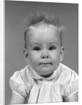 1960s head on portrait of baby girl in ruffled dress straight up hair looking at camera by Anonymous