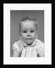 1960s head on portrait of baby girl in ruffled dress straight up hair looking at camera by Anonymous
