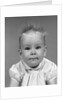 1960s head on portrait of baby girl in ruffled dress straight up hair looking at camera by Anonymous