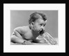 1950s baby sitting leaning forward drinking from bottle studio indoor by Anonymous