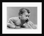 1950s baby sitting leaning forward drinking from bottle studio indoor by Anonymous