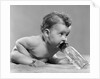 1950s baby sitting leaning forward drinking from bottle studio indoor by Anonymous