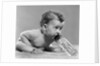 1950s baby sitting leaning forward drinking from bottle studio indoor by Anonymous