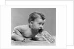 1950s baby sitting leaning forward drinking from bottle studio indoor by Anonymous