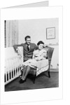 1930s 1940s mother sitting in chair in nursery baby 11 months on lap drinking from bottle father looking on leaning on crib by Anonymous