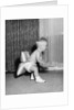 1950s laughing baby in diaper and shoes learning to walk with a pillow tied to his rear end by Anonymous