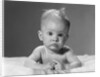 1960s portrait baby lying on stomach with messy hair and bulging eyes looking at camera by Anonymous